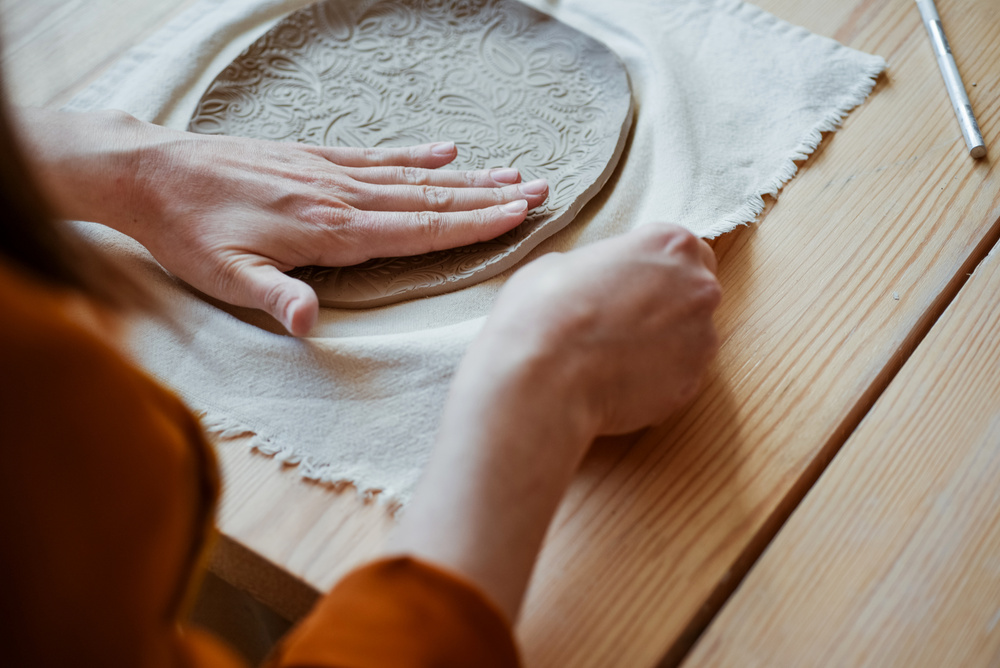 Hand moulding from white clay, Potter moulding an openwork plate